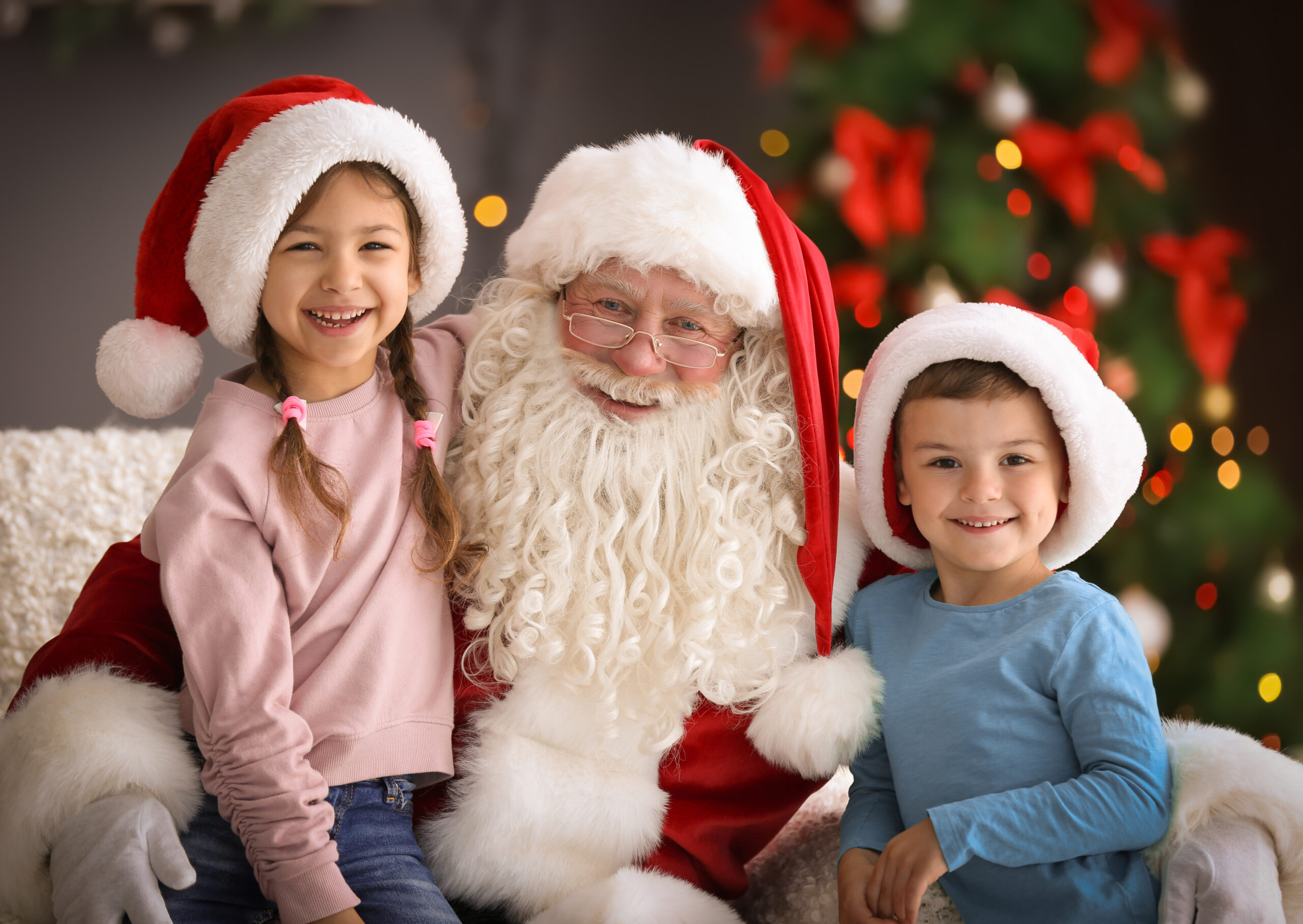 Little children sitting on authentic Santa Claus' knees indoors